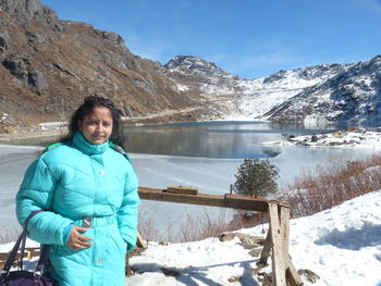 Portrait of woman standing on snowcapped mountains during winter