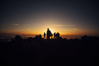 Silhouette people on beach against sky during sunset