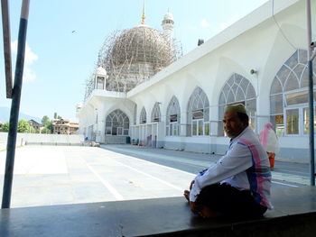 Man outside temple against sky in city