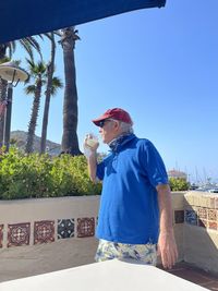 Man holding ice cream against blue sky