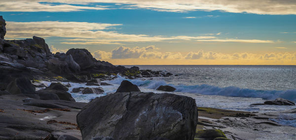 Rocks by sea against sky during sunset
