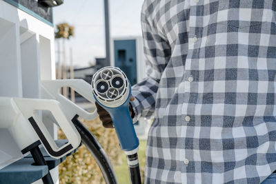 Man with electric car charger at station