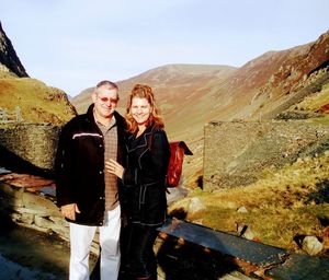 Portrait of friends standing on mountain against sky