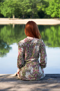 Young woman sitting on wooden pier looking at lake