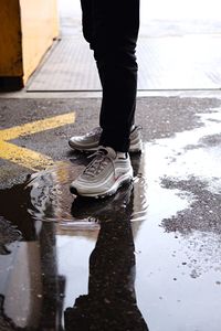 Low section of man standing on wet road