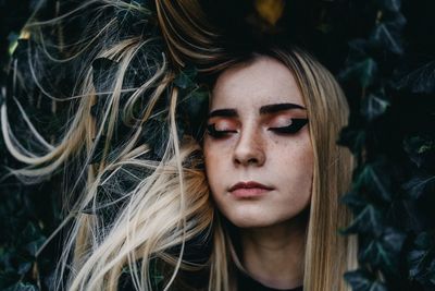 Young woman against plant