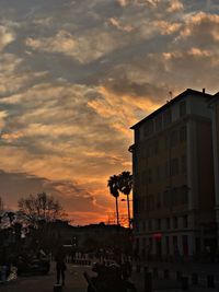 Street by buildings against sky during sunset