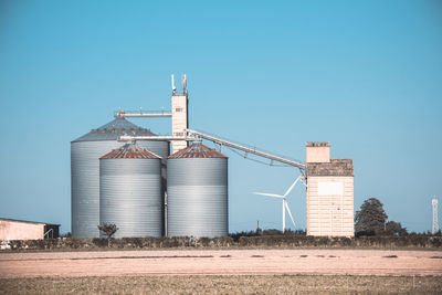 Factory on field against clear blue sky