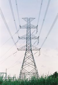 Low angle view of electricity pylon on field against sky