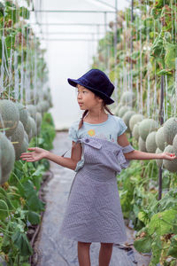 Cute girl standing amidst cantaloupes growing on farm