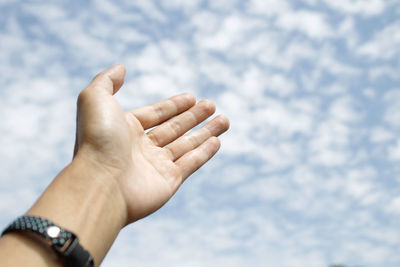 Close-up of human hand against sky