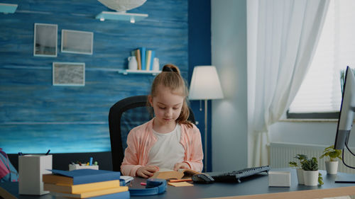 Rear view of woman using digital tablet while sitting on table