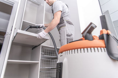 Midsection of man using vacuum at home