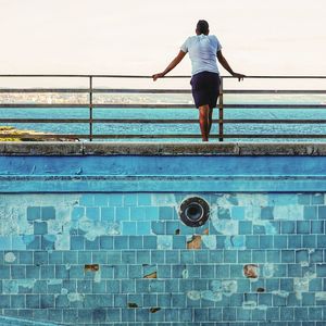 Full length rear view of man standing at swimming pool