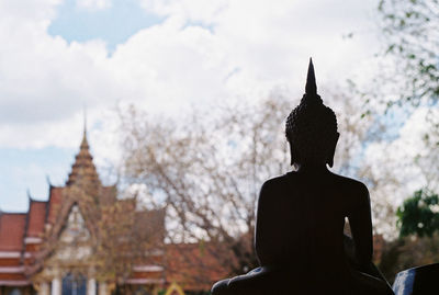 Rear view of statue against building and sky