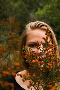 Close-up portrait of woman with red flower buds