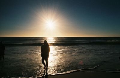 Rear view of silhouette person on beach against sky