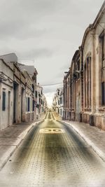 Empty alley amidst buildings in city against sky