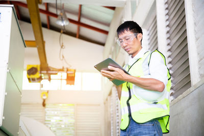 Male specialist engineer in high visibility vests using tablet computer.