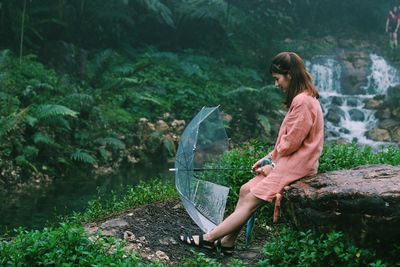 Woman on rock by lake against trees