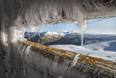 Icicles on snowcapped mountain against sky