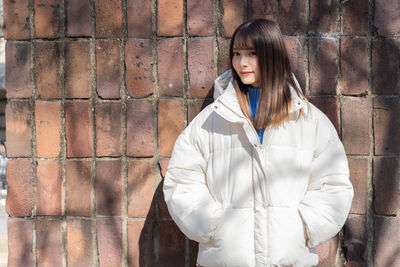 Young woman standing against wall