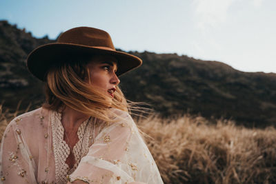 Thoughtful woman wearing hat while looking away on land