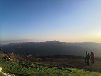 Rear view of men on landscape against clear sky