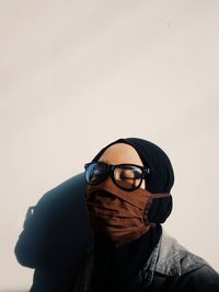 Close-up of woman wearing flu mask standing by wall