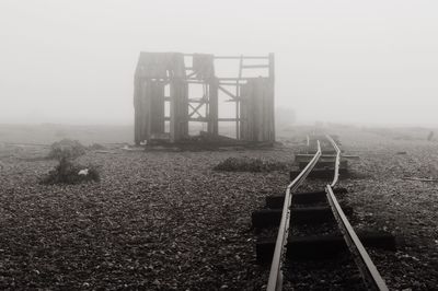Lifeguard hut on landscape against sky during foggy weather