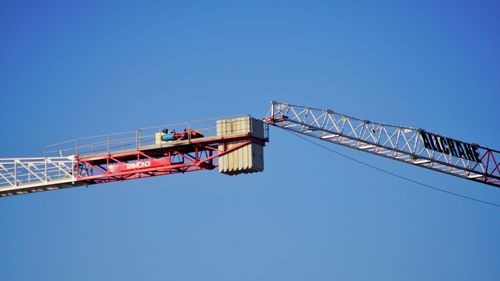 Low angle view of crane against clear blue sky