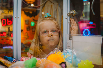 Little girl looking through glass of claw machine