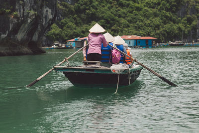 Rear view of people traveling in boat sailing over river
