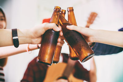 Close-up of friends toasting beer bottles