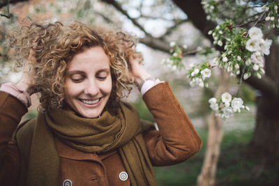 Smiling woman with hands in hair at park