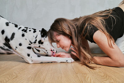 Side view of young woman with dog on hardwood floor