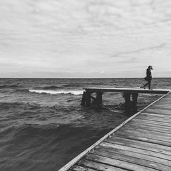 Pier on sea against cloudy sky