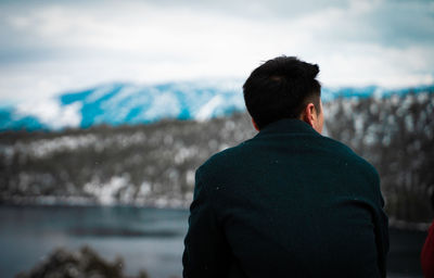 Rear view of man looking at sea against sky