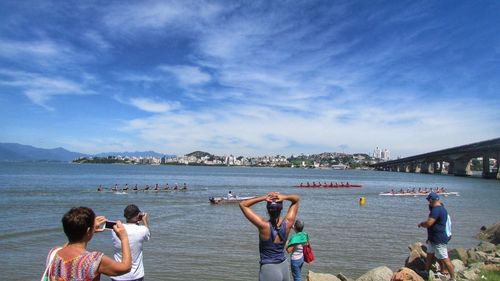 People enjoying on beach against sky