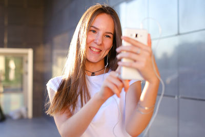 Portrait of young woman standing against wall