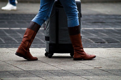 Low section of woman wearing boots walking on footpath