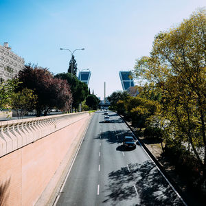 Street amidst trees against sky in city