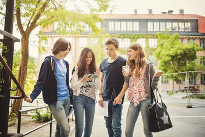 Happy teenagers using smart phone on street