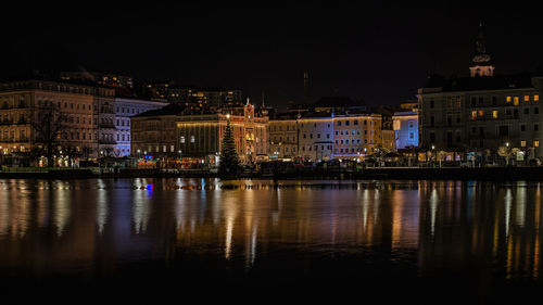 Illuminated buildings by river at night