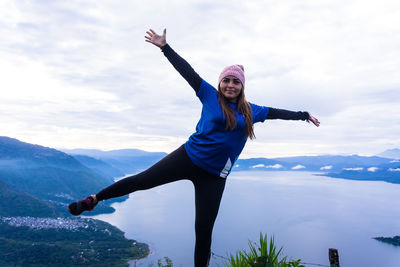 Full length of young woman standing on mountain against sky