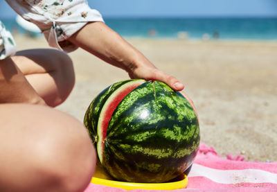 Midsection of woman holding bauble at beach