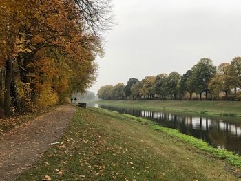 Road by canal against sky during autumn