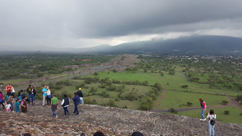 People on mountain against cloudy sky