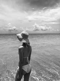 Rear view of man standing in sea against sky