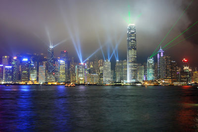 Illuminated city by river at night